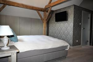 a bedroom with a bed and a tv on the wall at Hoeve Lavigne in Wellen