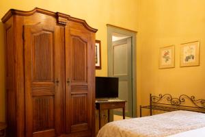 um quarto com uma cama, um armário de madeira e uma televisão em Castello di Castellengo em Cossato