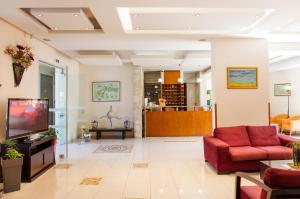 sala de estar con sofá rojo y TV en Ilyssion Holidays Hotel en Ialyssos