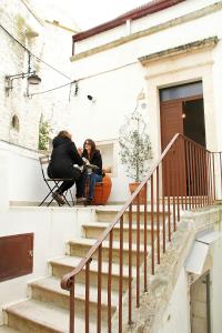 dos personas sentadas en las escaleras de un edificio en Lo studio di Nonno en Noci