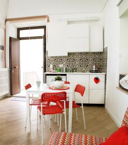 cocina con mesa blanca y sillas rojas en Lo studio di Nonno en Noci