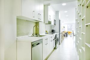 una cocina con armarios blancos y fregadero en Charming Madrid La Elipa - 3 dormitorios, en Madrid