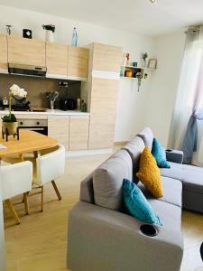een woonkamer met een grijze bank en een tafel bij Maisonnette indépendante au calme in Vittel