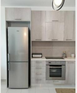 a kitchen with a stainless steel refrigerator and white cabinets at Alkyonis house in Triovasálos