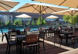an outdoor patio with tables and chairs and umbrellas at Crowne Plaza Montpellier Corum, an IHG Hotel in Montpellier