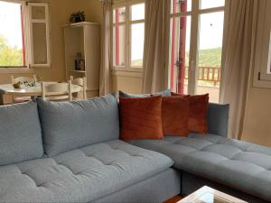 Pandora Villa في فاثي: أريكة زرقاء في غرفة المعيشة مع نوافذ
