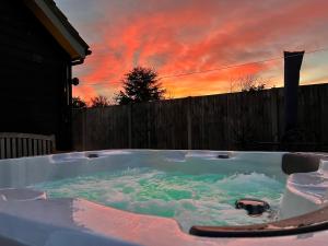a jacuzzi tub with a sunset in the background at Saving Grace with private hot tub in Bawdeswell