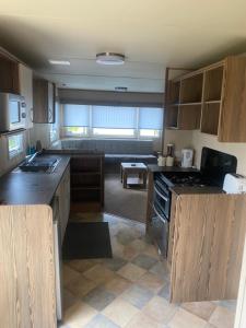 a kitchen with wooden cabinets and a stove top oven at BrookeView Caravan Rental, Seton Sands in Port Seton