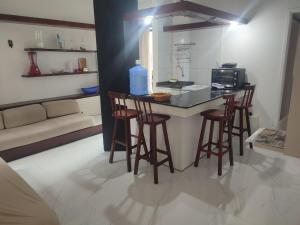 a kitchen with a bar with stools and a microwave at Apartamento Farol Barra Flat in Salvador