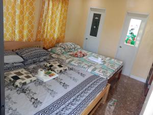 1 dormitorio con 2 camas y bandeja de comida. en Balai Mariacaria Pension House, en Guindulman