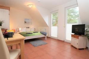 a room with a bed and a desk with a television at "Strandkoje" Strandkoje, App 07 in Neuhaus