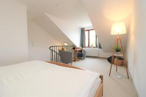 a white bedroom with a bed and a living room at Ferienzimmeranlage Deutsches Haus Deutsches Haus App 37 in Wustrow