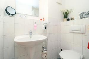 Baño blanco con lavabo y aseo en Ferienzimmeranlage Deutsches Haus Deutsches Haus App 22, en Wustrow