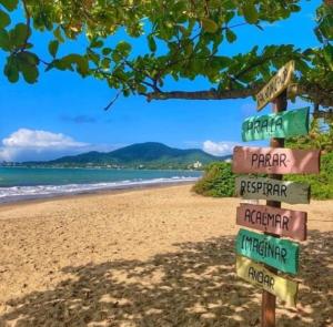 a street sign on a beach with the ocean at Pousada Casa Amarela Brisa Parque in Penha