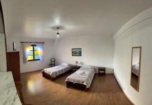 a large room with two beds and a mirror at Pousada da Brigida in Campos do Jordão