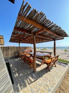 una mesa y sillas bajo una sombrilla de madera en la playa en Casa Aloha Punta Sal en La Bocana