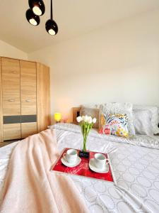 a bed with a tray with two cups and flowers on it at Downtown Apartments Monroe in Rzeszów