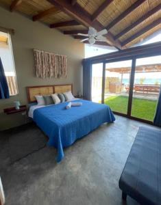 1 dormitorio con cama azul y ventana grande en Casa Aloha Punta Sal en La Bocana