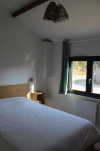 ein Schlafzimmer mit einem weißen Bett und einem Fenster in der Unterkunft Maison 8 personnes à 100 m de la plage de la Clère in Le Grand Vieil