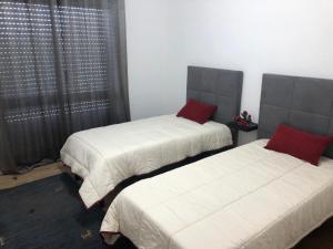 - une chambre avec 2 lits dotés de draps blancs et d'oreillers rouges dans l'établissement Apartamento Rio Minho, à Vila Nova de Cerveira