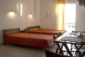 a hotel room with two beds and a table and a dining room at Sirius in Kanali