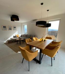 a living room with a wooden table and yellow chairs at Apartmán s vyhliadkou in Bojnice