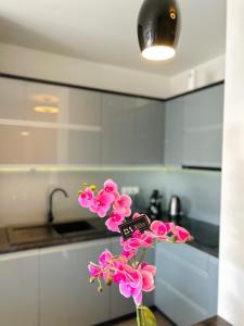 a vase filled with pink flowers in a kitchen at Downtown Apartments Monroe in Rzeszów