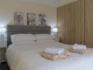 ein großes weißes Bett mit zwei Handtüchern darauf in der Unterkunft Poppy Lodge Glendevon Scotland in Glendevon