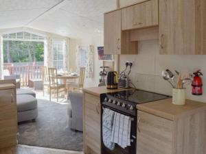 a kitchen with a stove top oven next to a living room at Poppy Lodge Glendevon Scotland in Glendevon