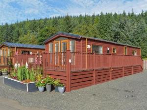 a large wooden cabin with a fence and flowers at Poppy Lodge Glendevon Scotland in Glendevon