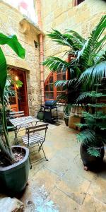 a patio with benches and plants in front of a building at Il Mithna farmhouse with indoor heated jacuzzi pool in Għarb
