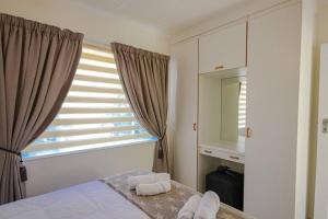 a bedroom with a bed and a window with towels at The Lemon Tree Oasis - Solar in Centurion