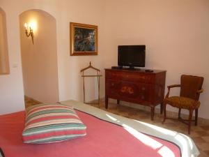 een slaapkamer met een bed, een tv en een stoel bij Auberge de Correns in Correns