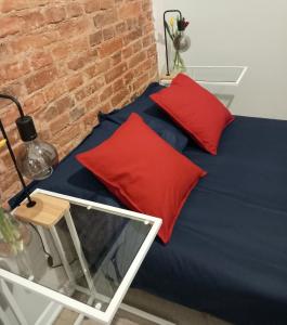 a blue bed with red pillows and a table at Hola Apartamenty Legionow in Łódź