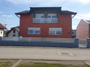 a red house with a white fence in front of it at APARTMAN SOFIA in Županja