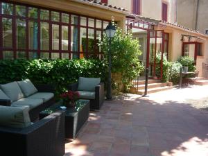 un patio con divani e tavoli di fronte a un edificio di Auberge de Correns a Correns