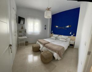 um quarto com 2 camas e uma parede azul em Hoyo 20 de La Monacilla Golf em Huelva