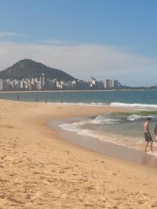Un par de personas caminando por la playa en Espaçosa kitnet em itapua 10 min da praia., en Vila Velha