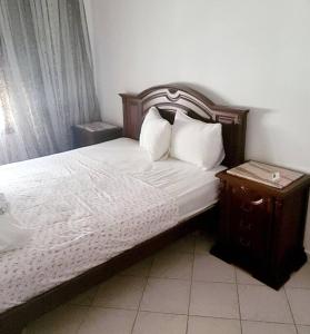 Schlafzimmer mit einem Bett mit einem Kopfteil aus Holz und einem Nachttisch in der Unterkunft La villa de la mer in Sidi Bou Jobline