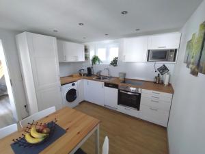 a kitchen with white cabinets and a table with a bowl of fruit at Das Mini-Haus im Herzen Großostheims in Großostheim