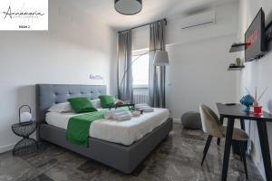 Schlafzimmer mit einem Bett mit grünen Kissen und einem Schreibtisch in der Unterkunft Annamaria - Central Station Charming accommodation in Bari
