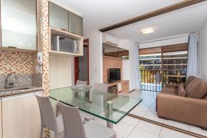 uma cozinha e sala de estar com uma mesa de vidro em Nannai Residence by AFT em Porto de Galinhas