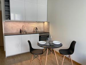 uma cozinha com uma mesa e cadeiras e um lavatório em Pearl - new and cosy apartment close to Center em Riga