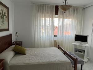 1 dormitorio con 1 cama, TV y ventana en CampoFontal apartamento, en Boiro