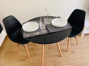 a black table with chairs and plates and glasses on it at Pearl - new and cosy apartment close to Center in Rīga