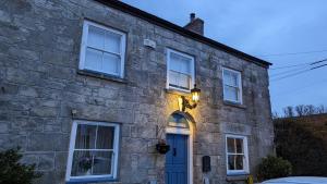 uma casa de pedra com uma porta azul e janelas em Britannia House Vintage B&B Cornwall em Helston