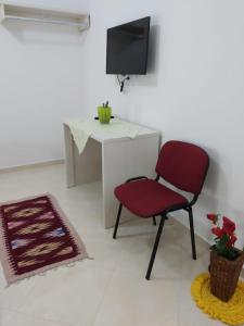 einen roten Stuhl in einem Zimmer mit einem Schreibtisch in der Unterkunft Olive B&B in Berat
