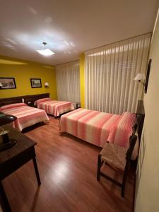 Habitación de hotel con 2 camas y mesa en HOSTAL EL CHOCOLATERO, en Castildelgado