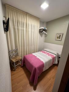 um quarto com uma cama com um cobertor rosa em HOSTAL EL CHOCOLATERO em Castildelgado