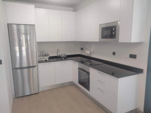a kitchen with white cabinets and a stainless steel refrigerator at Anam Cara House in Serantes